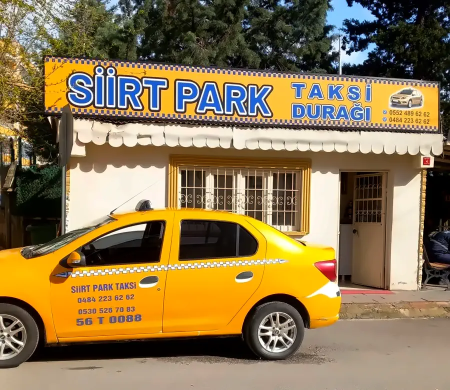 Tabelasında Siirt Park Taksi Durağı yazan beyaz durak binası ve önünde bekleyen sarı taksi